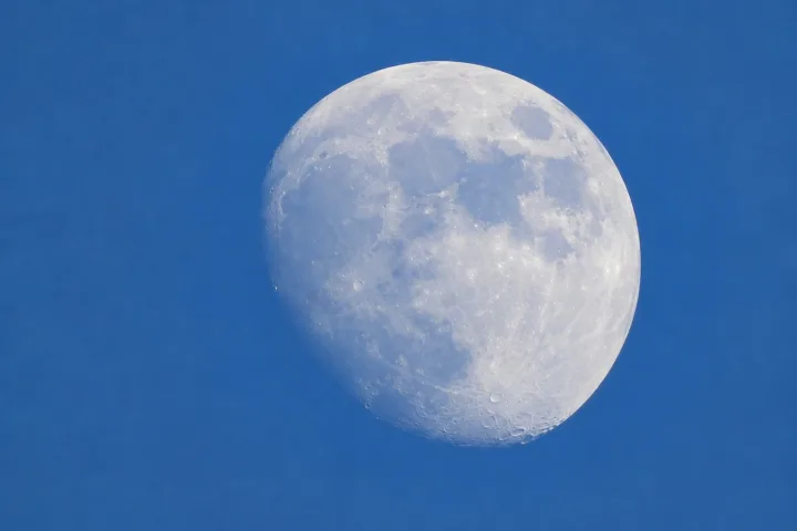 La Luna pallida visibile in pieno giorno contro un cielo azzurro luminoso